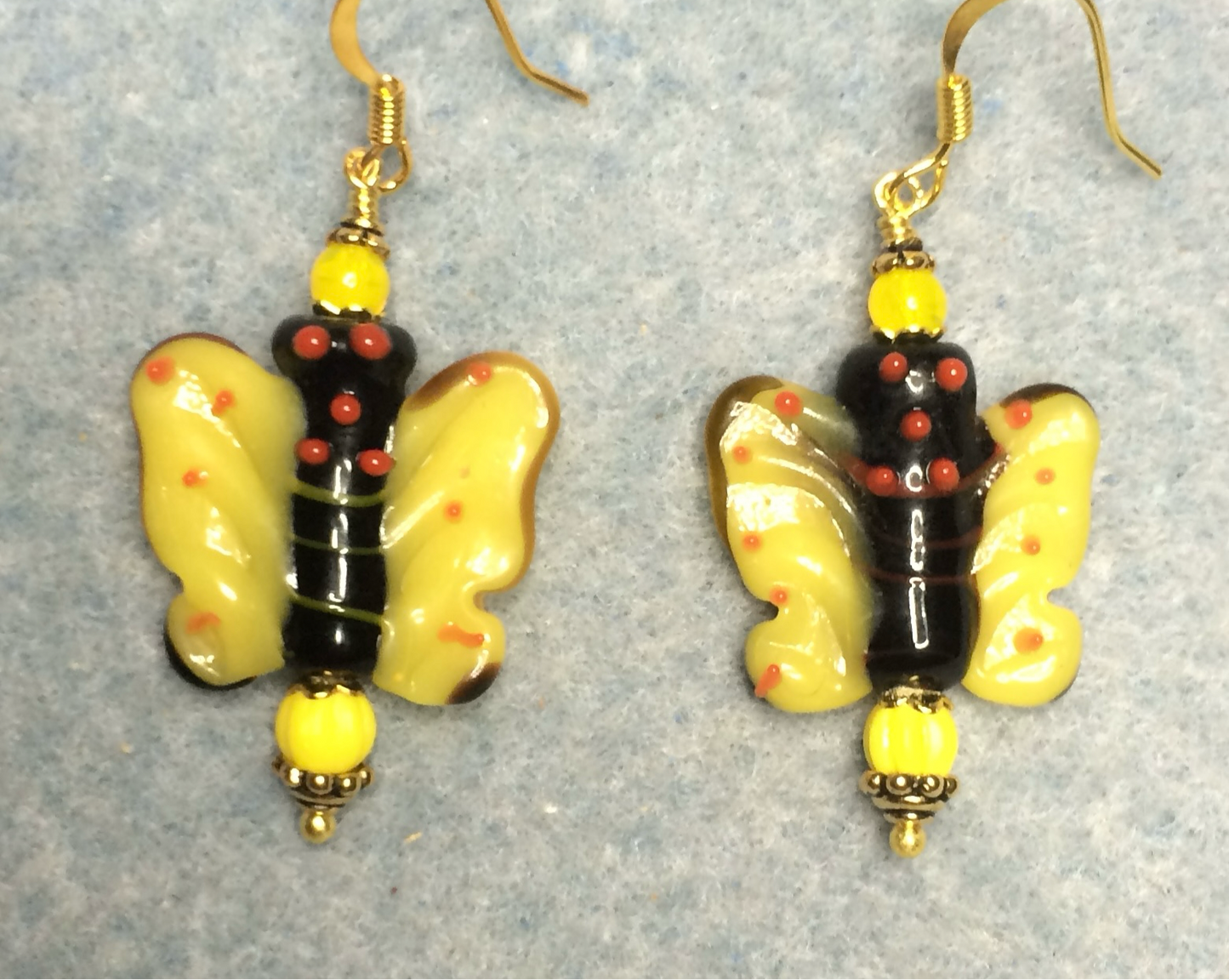 Yellow and black lamp work butterfly bead earrings adorned with yellow Czech glass beads.