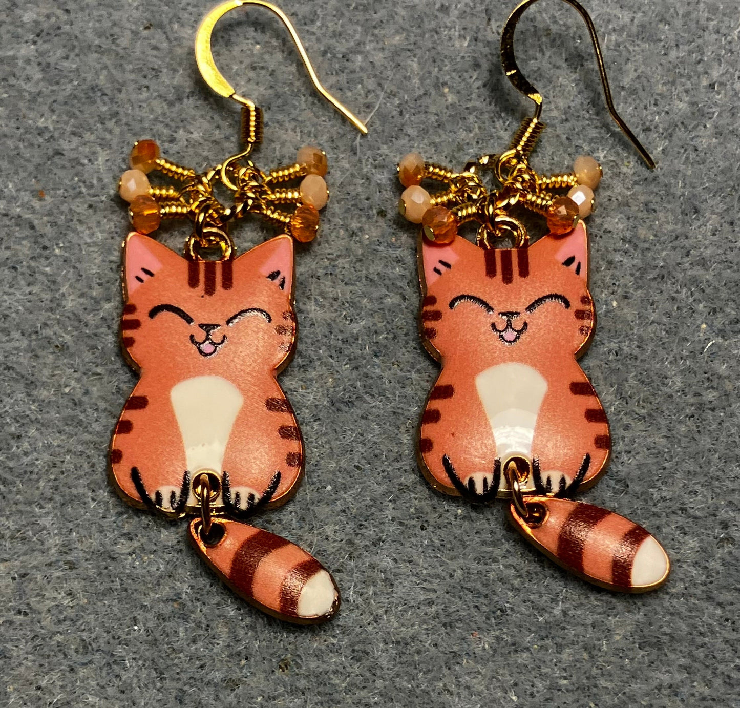Orange, brown, and white enamel tabby cat charm earrings adorned with tiny dangling orange and white Chinese crystal beads.