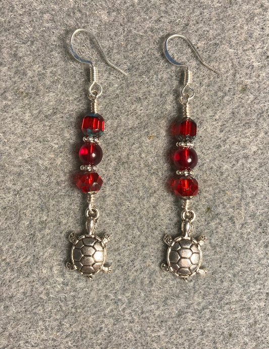 Silver turtle charm earrings adorned with red Czech glass beads.