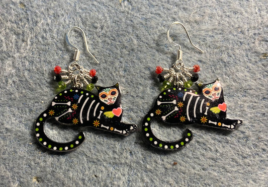 Black, green, and red enamel skeleton cat charm earrings adorned with tiny dangling black, green, and red Chinese crystal beads.