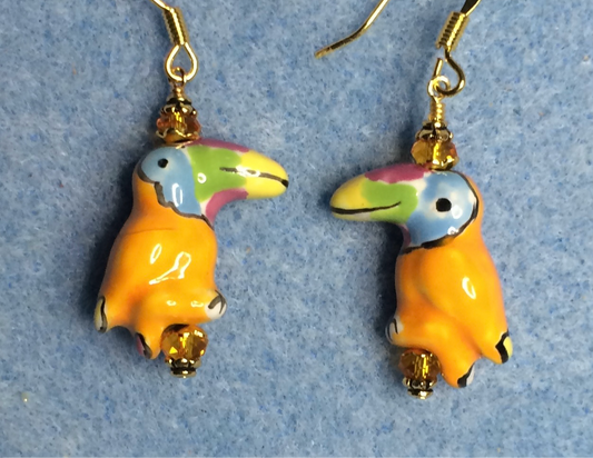 Tangerine, blue, green, and yellow ceramic toucan bead earrings adorned with tangerine Chinese crystal beads.