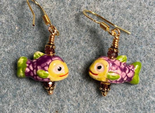 Small purple, yellow, and olive green ceramic fish bead earrings adorned with purple Chinese crystal beads.