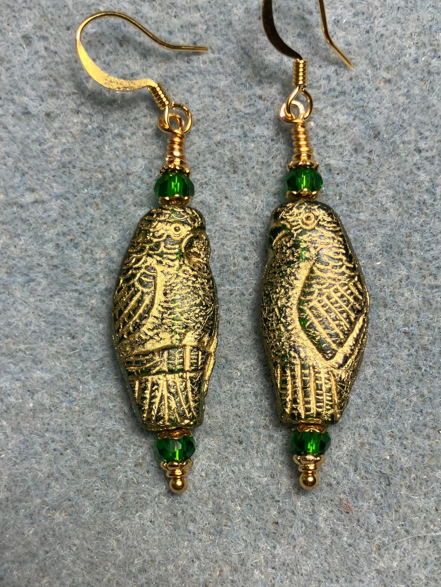 Large green (with gold wash) Czech glass parrot bead earrings adorned with green Chinese crystal beads.