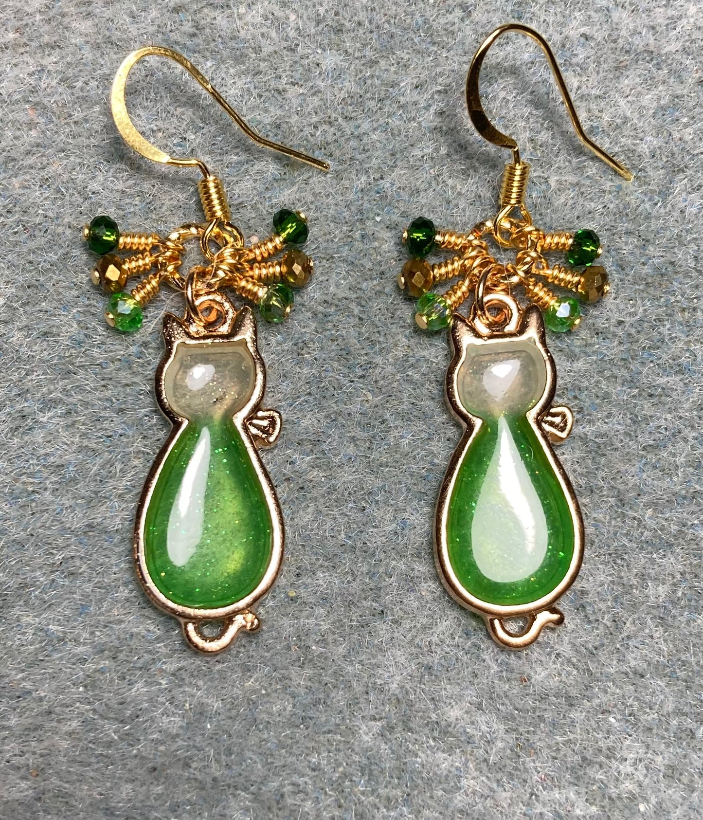 Green and gold sparkly resin cat charm earrings adorned with small dangling green and gold Chinese crystal beads.