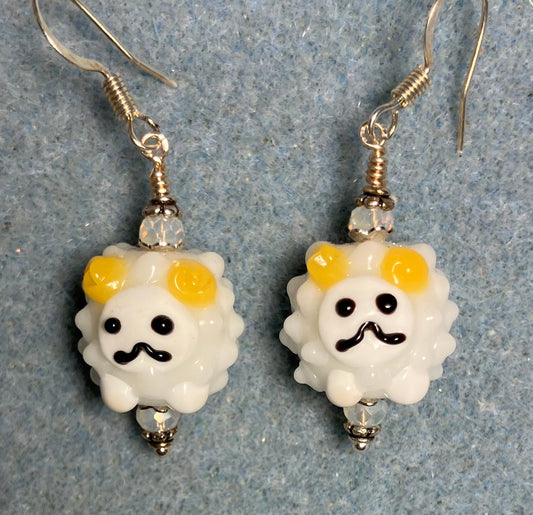 White, yellow, and black lamp work sheep bead earrings adorned with white Chinese crystal beads.