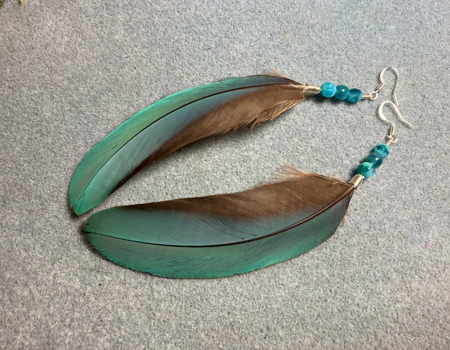 Turquoise blue macaw feather earrings adorned with turquoise Czech glass beads.
