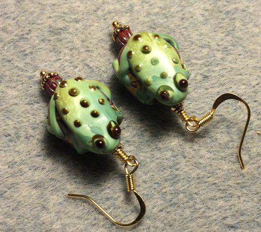 Large green and dark red lamp work frog bead earrings adorned with red Picasso Czech glass beads.