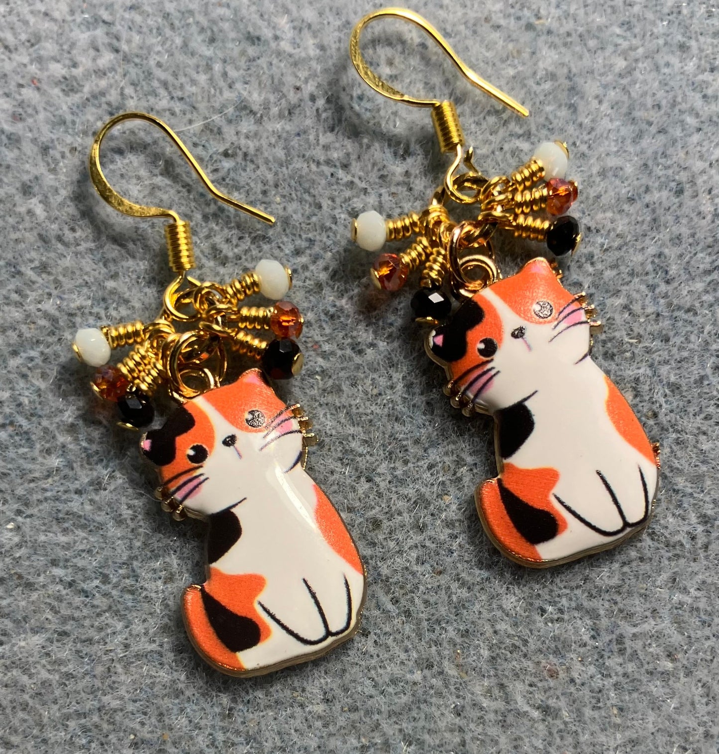 Orange, white, and black enamel calico cat charm earrings adorned with tiny dangling orange, white, and black Chinese crystal beads.