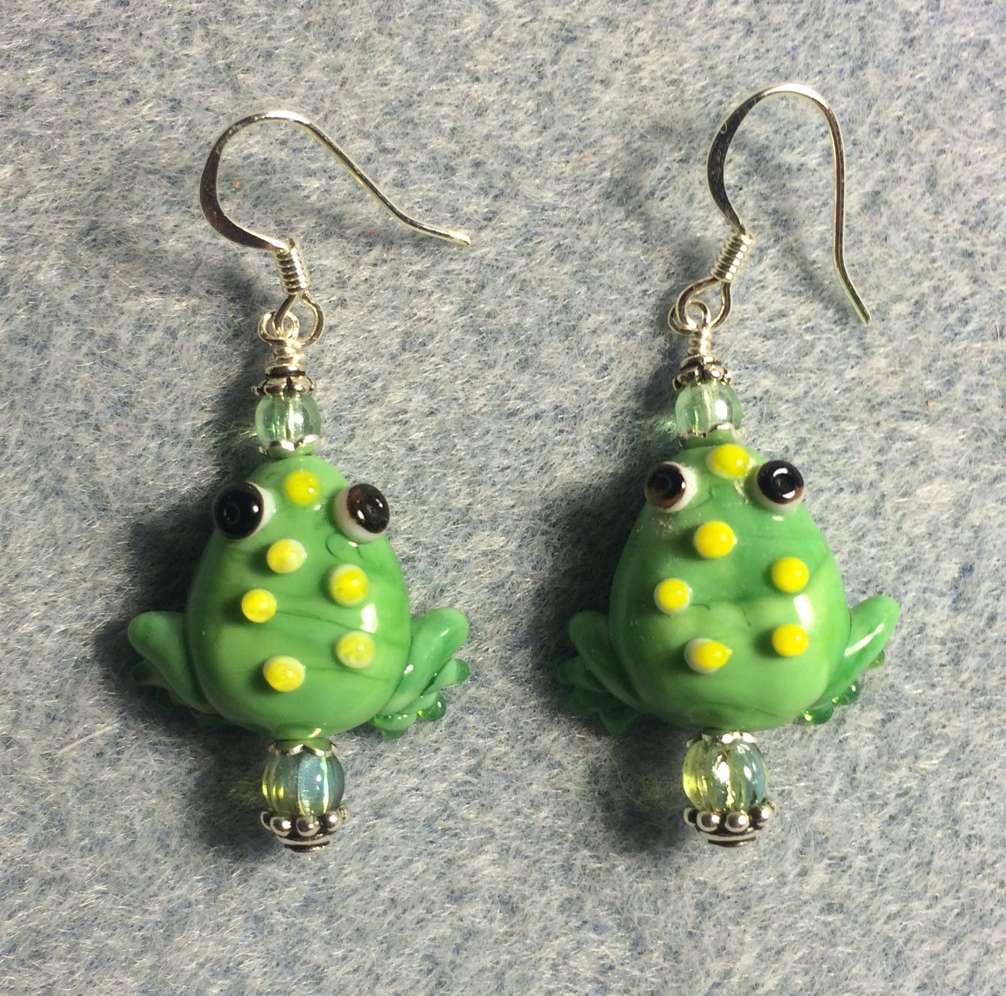 Opaque light green lamp work frog bead earrings adorned with light green Czech glass beads.