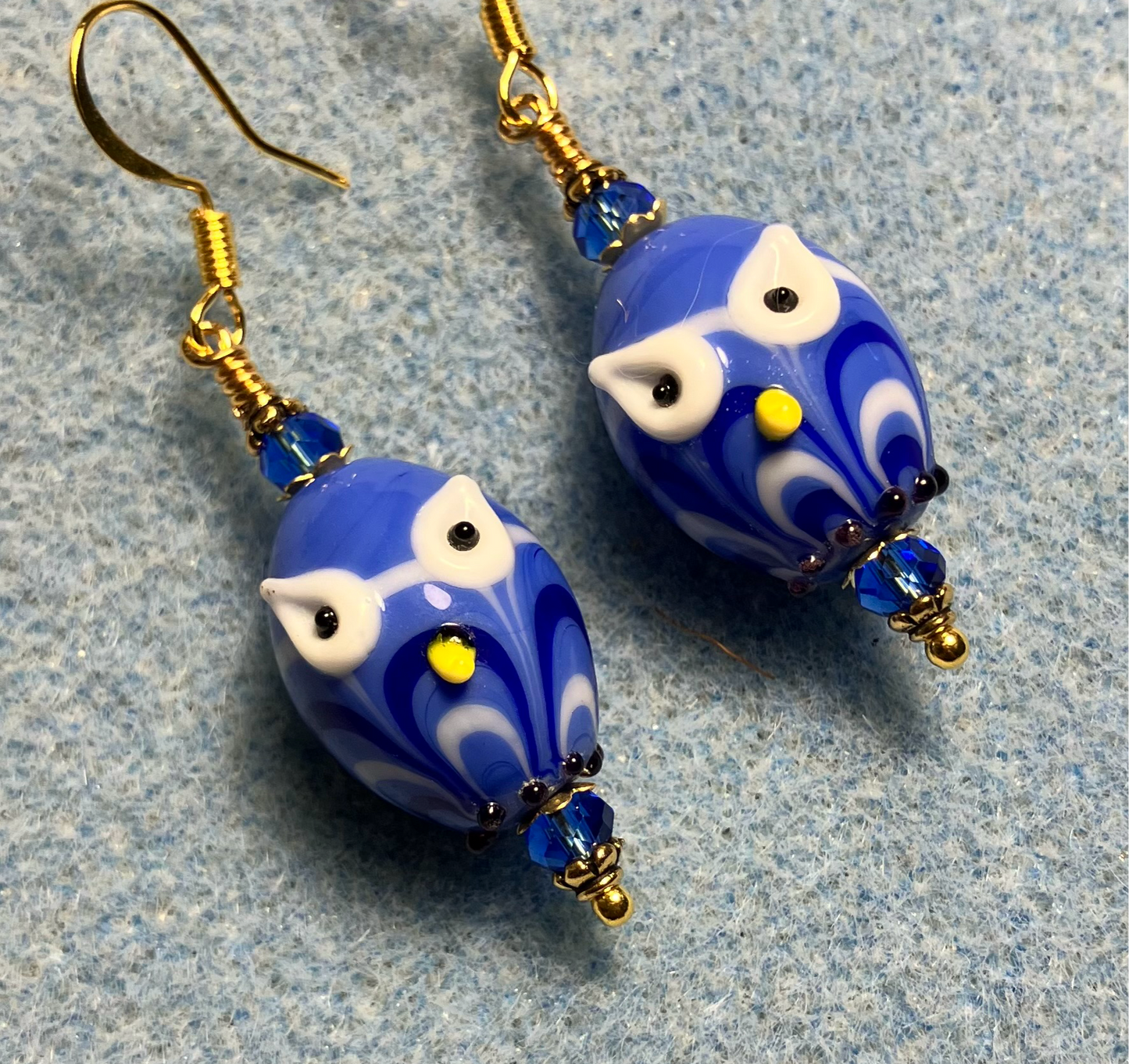 Bright blue lamp work owl bead earrings adorned with bright blue Chinese crystal beads.