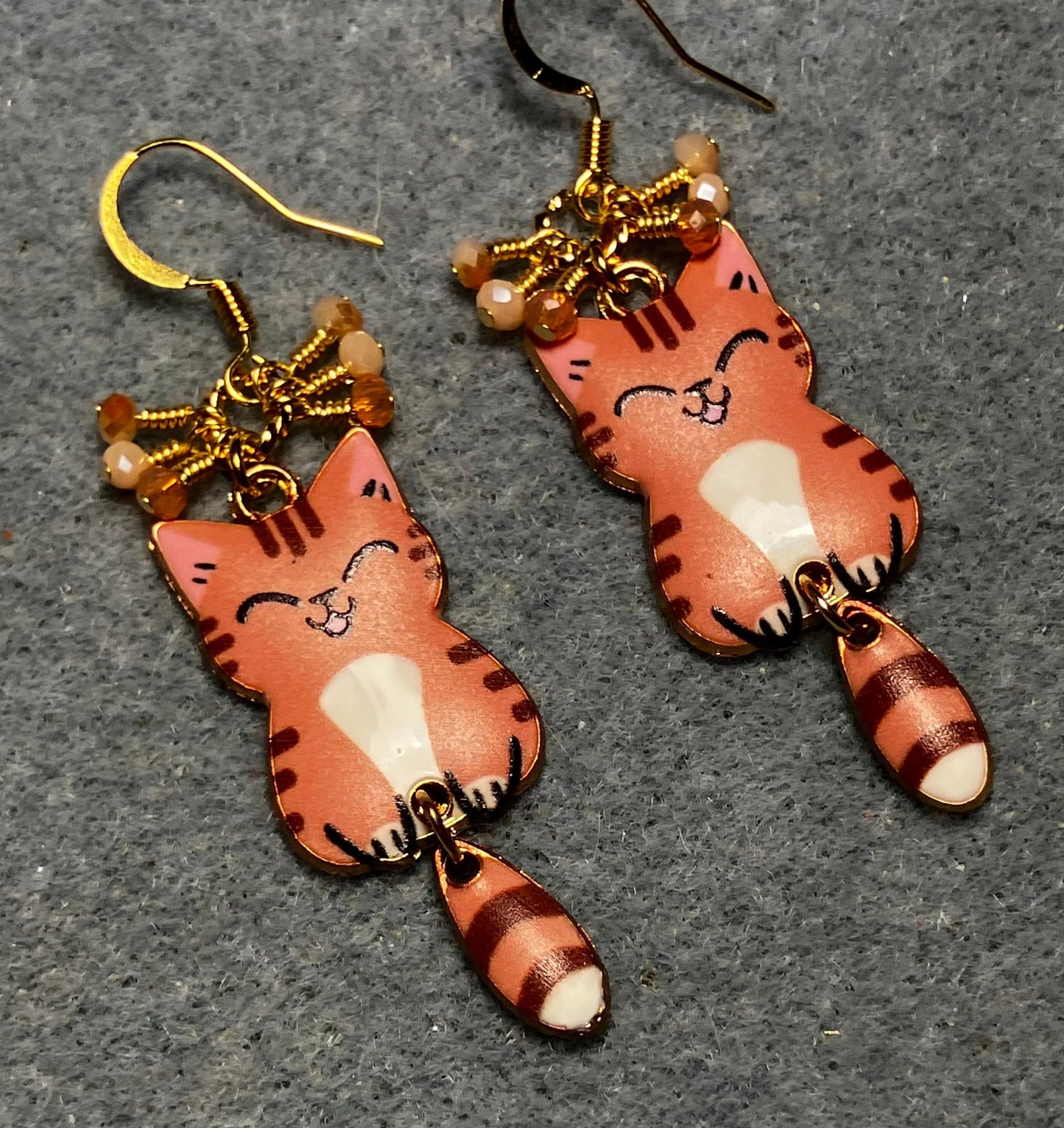 Orange, brown, and white enamel tabby cat charm earrings adorned with tiny dangling orange and white Chinese crystal beads.
