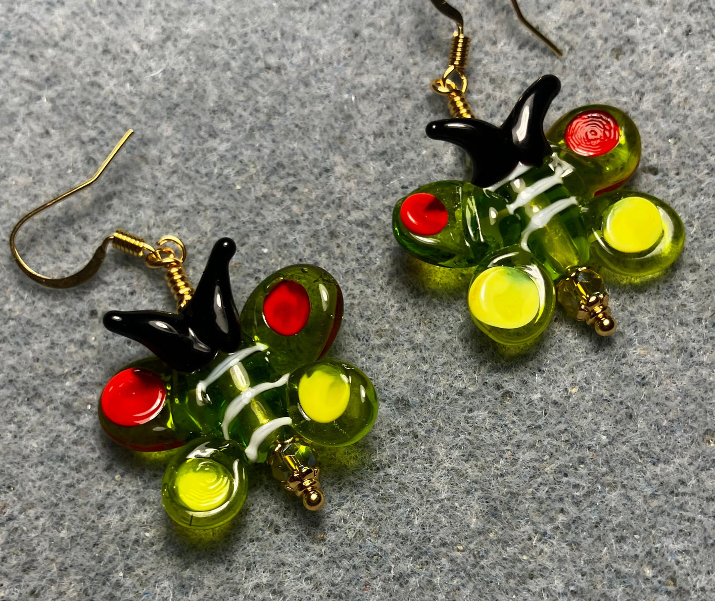 Olive green, red, yellow, and black lamp work butterfly bead earrings adorned with olive green Czech glass beads.
