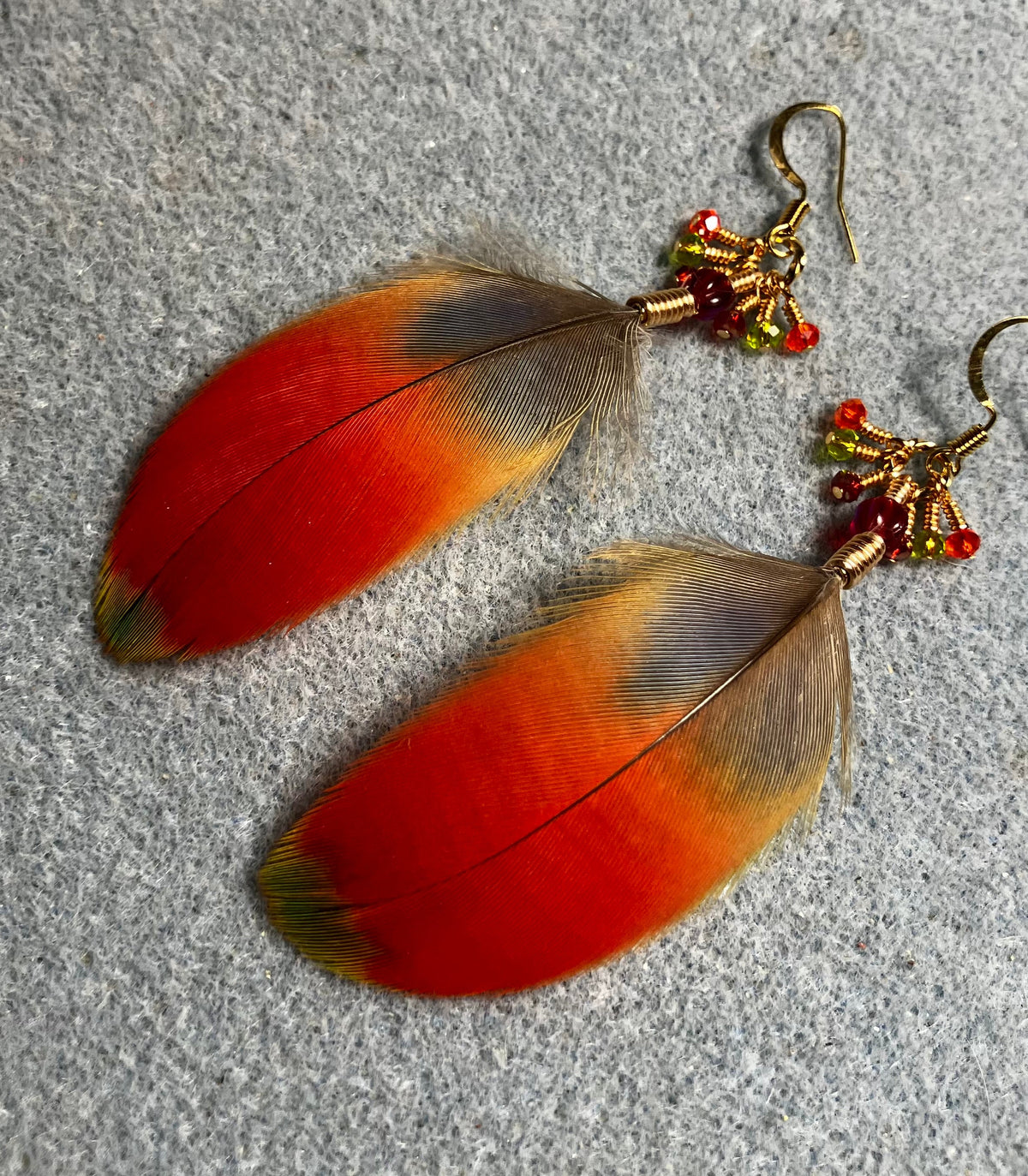 Red and green scarlet macaw feather earrings adorned with red Chinese crystal beads and tiny dangling red and green Chinese crystal beads.