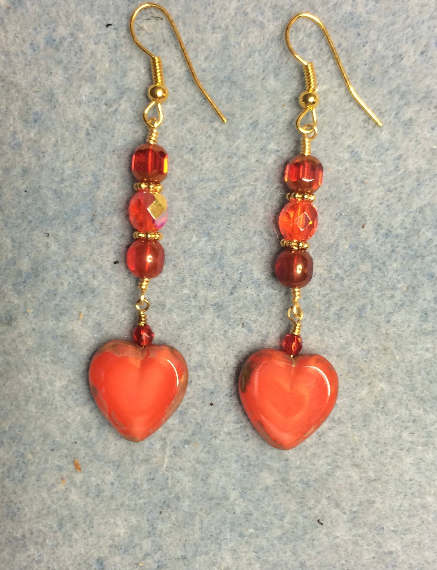 Opaque orange red Czech glass heart bead earrings adorned with red Czech glass beads.