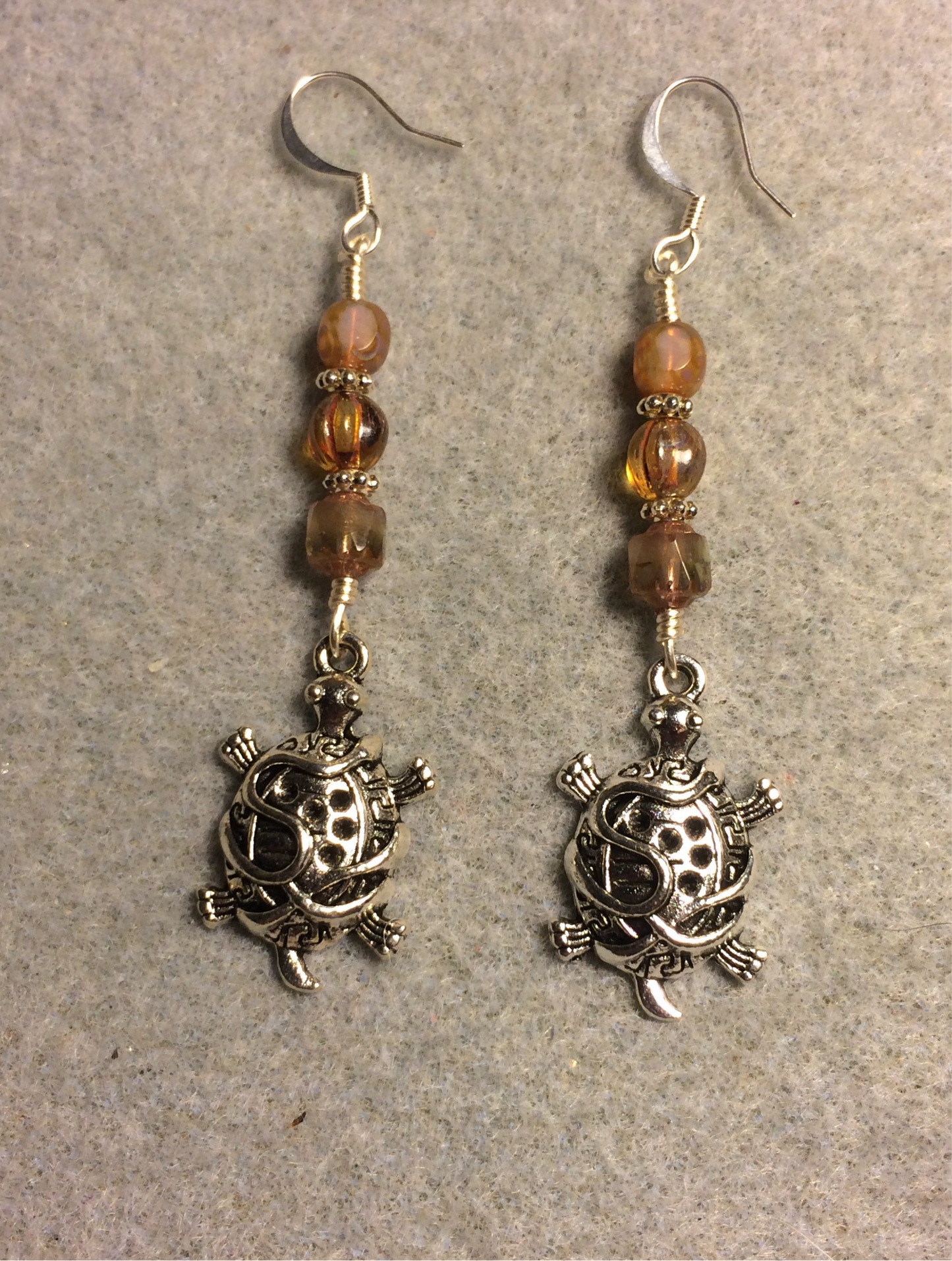 Ornate silver tortoise charm earrings adorned with milky beige Czech glass beads