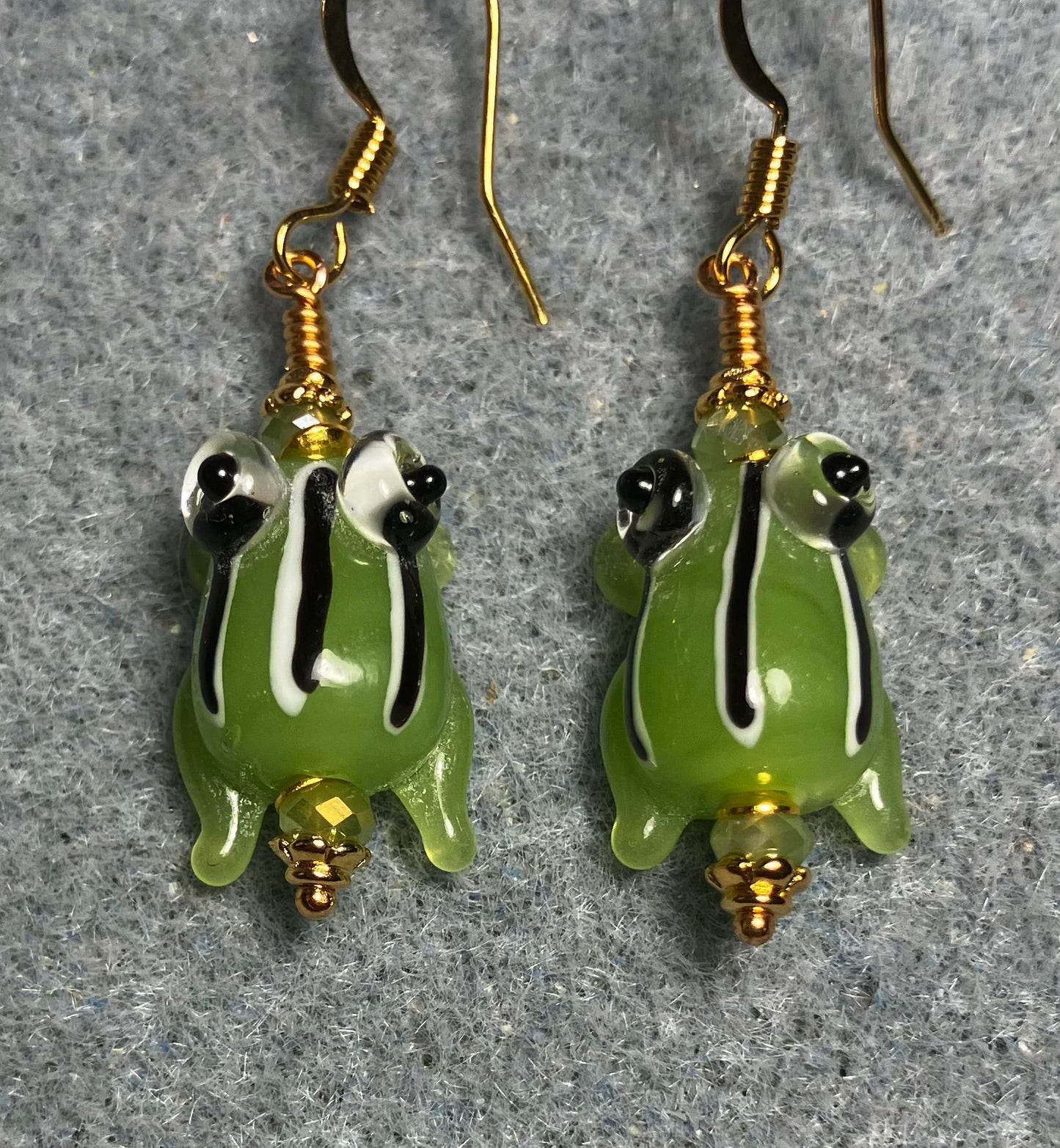 Very small opaque olive green with black and white stripes lamp work frog bead earrings adorned with olive green Chinese crystal beads.