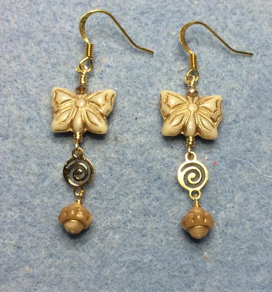 Beige Czech glass butterfly bead earrings adorned with gold swirly connectors and beige Czech glass Saturn beads.