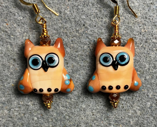 Beige, caramel, and blue lamp work owl bead earrings adorned with beige Chinese crystal beads.