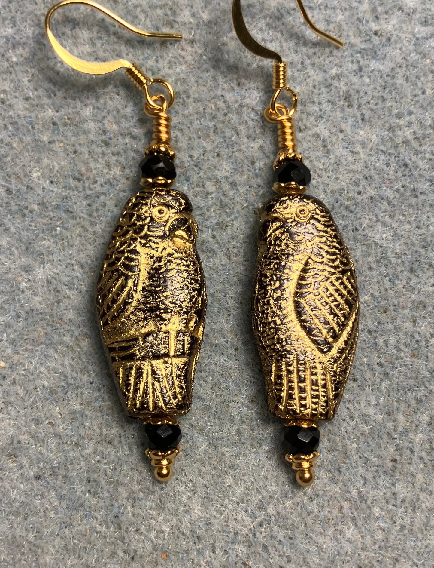 Large black (with gold wash) Czech glass parrot bead earrings adorned with black Chinese crystal beads.