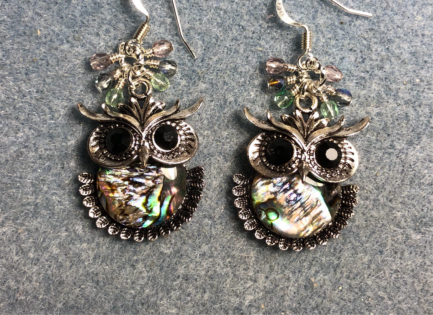 Silver and abalone owl charm earrings adorned with small dangling light green and violet Czech glass beads.