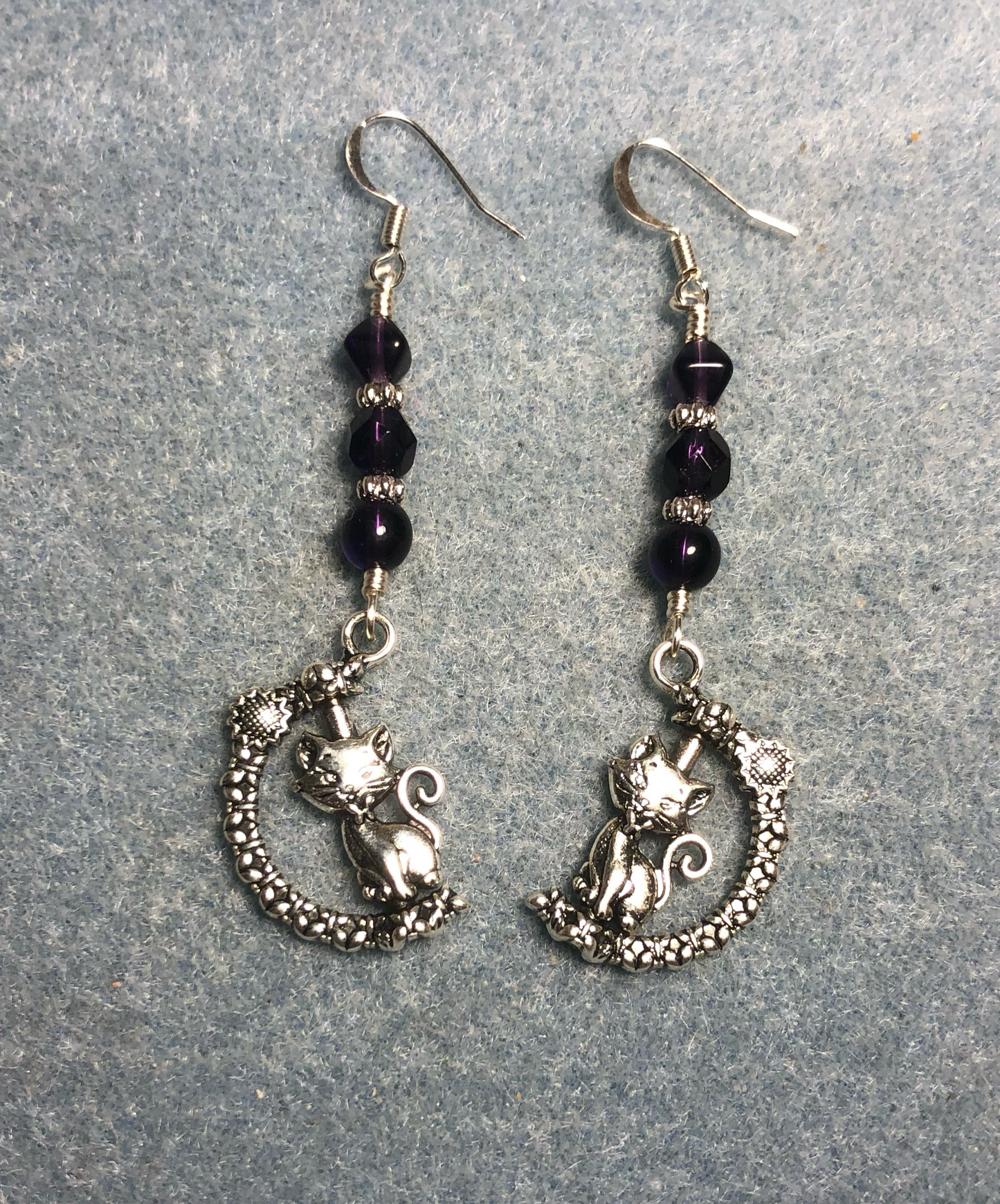 Silver spinning cat charm earrings adorned with grape purple Czech glass beads.