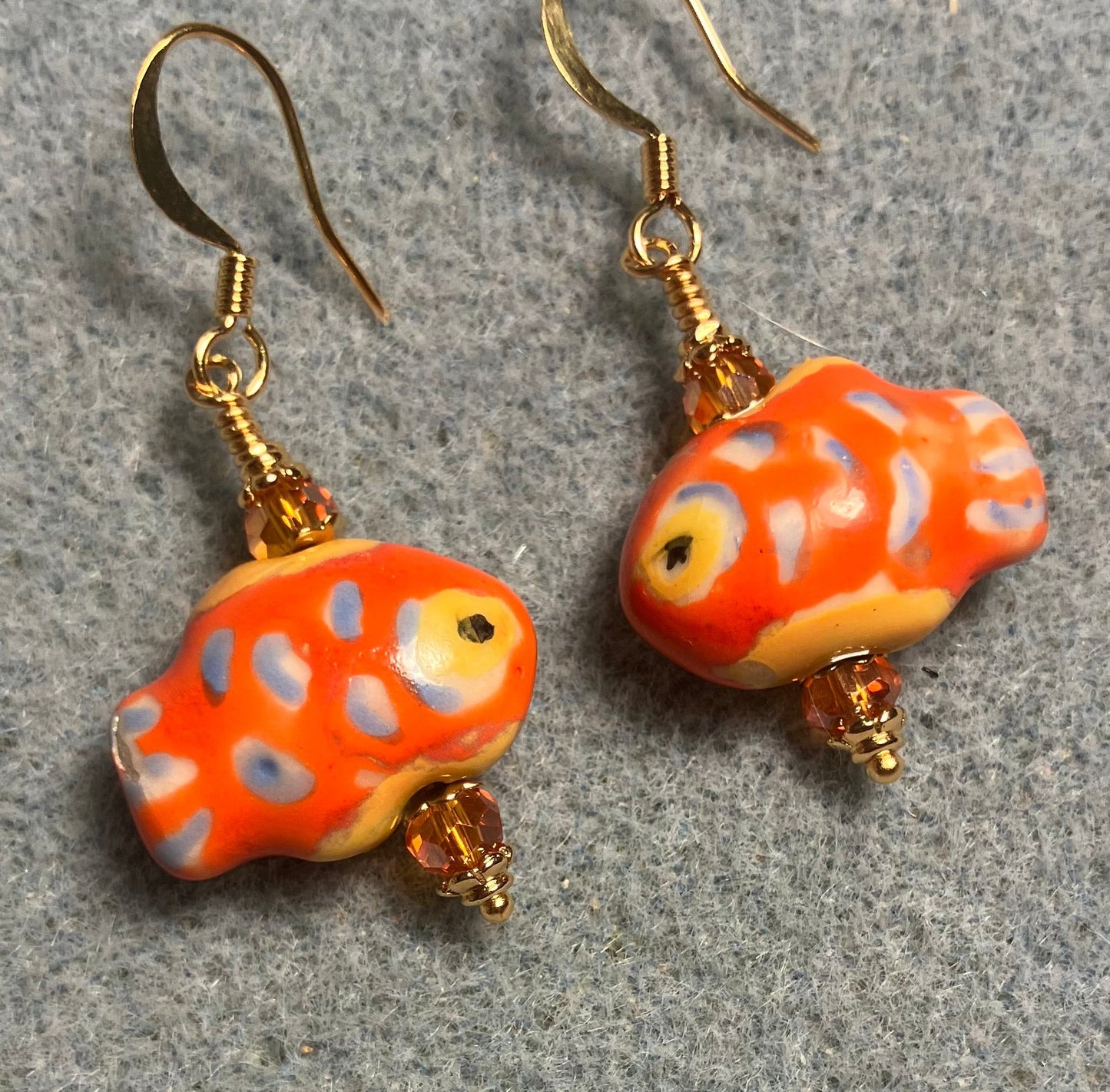 Orange, blue, and yellow ceramic spotted fish bead earrings adorned with orange Chinese crystal beads.