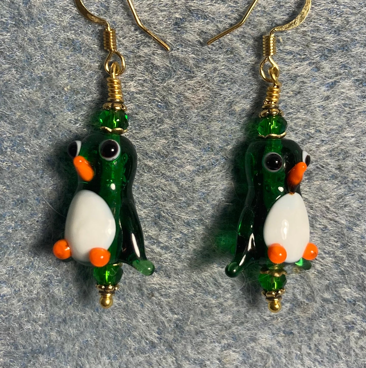 Translucent green and white lamp work penguin bead earrings adorned with green Chinese crystal beads.