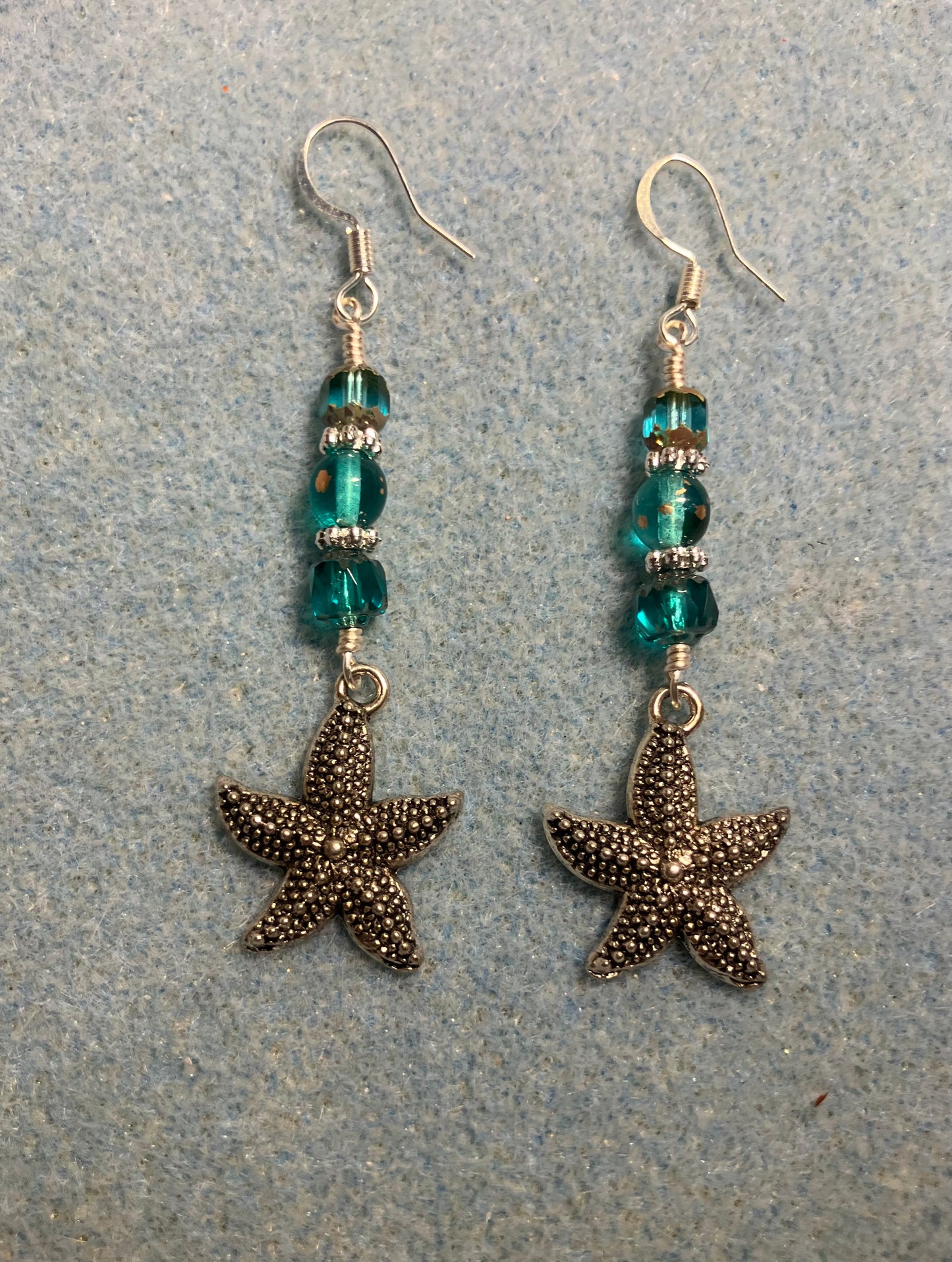 Silver starfish charm earrings adorned with teal Czech glass beads.