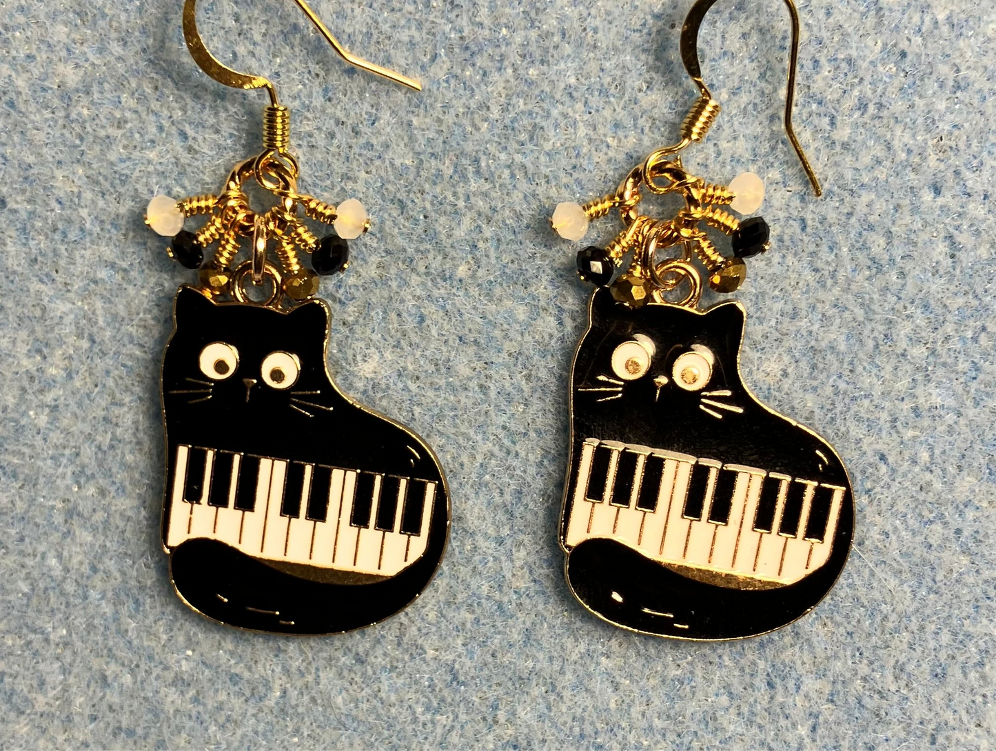 Black and white enamel piano cats charm earrings adorned with tiny dangling black, white, and gold Chinese crystal beads.