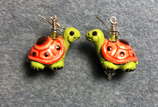 Large light olive green and orange ceramic turtle bead earrings adorned with olive green Czech glass beads.