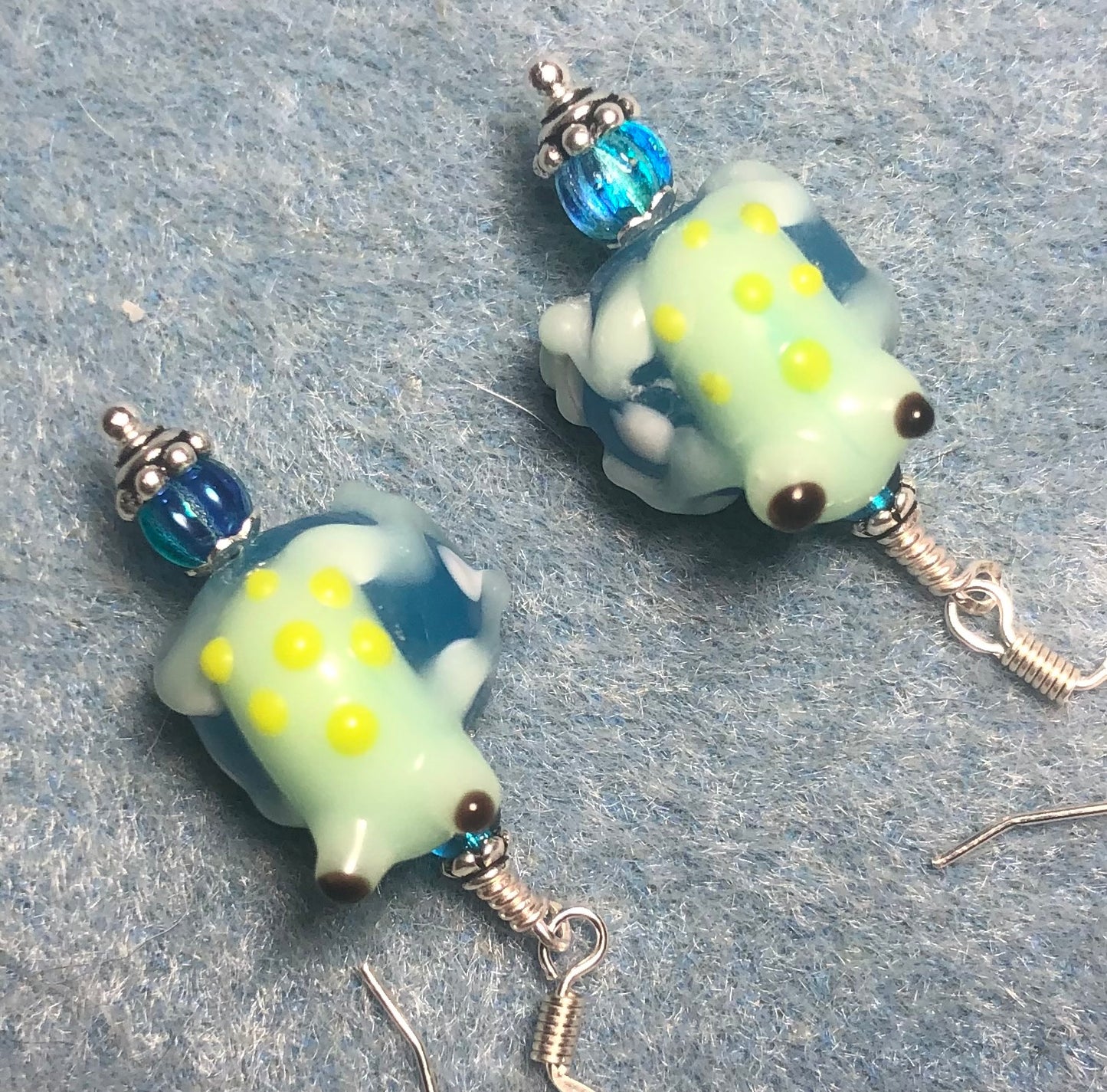 Turquoise, white, and light green lamp work frog bead earrings adorned with turquoise Czech glass beads.