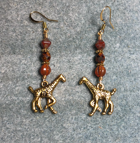 Gold giraffe charm earrings adorned with orange Czech glass beads