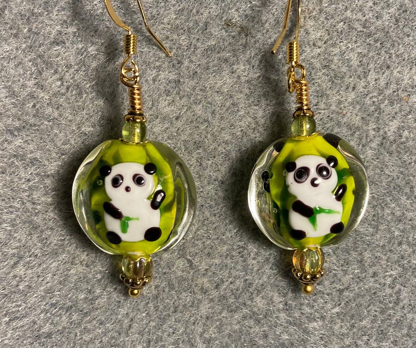 Green, black, and white lamp work panda bear bead earrings adorned with olive green Czech glass beads.