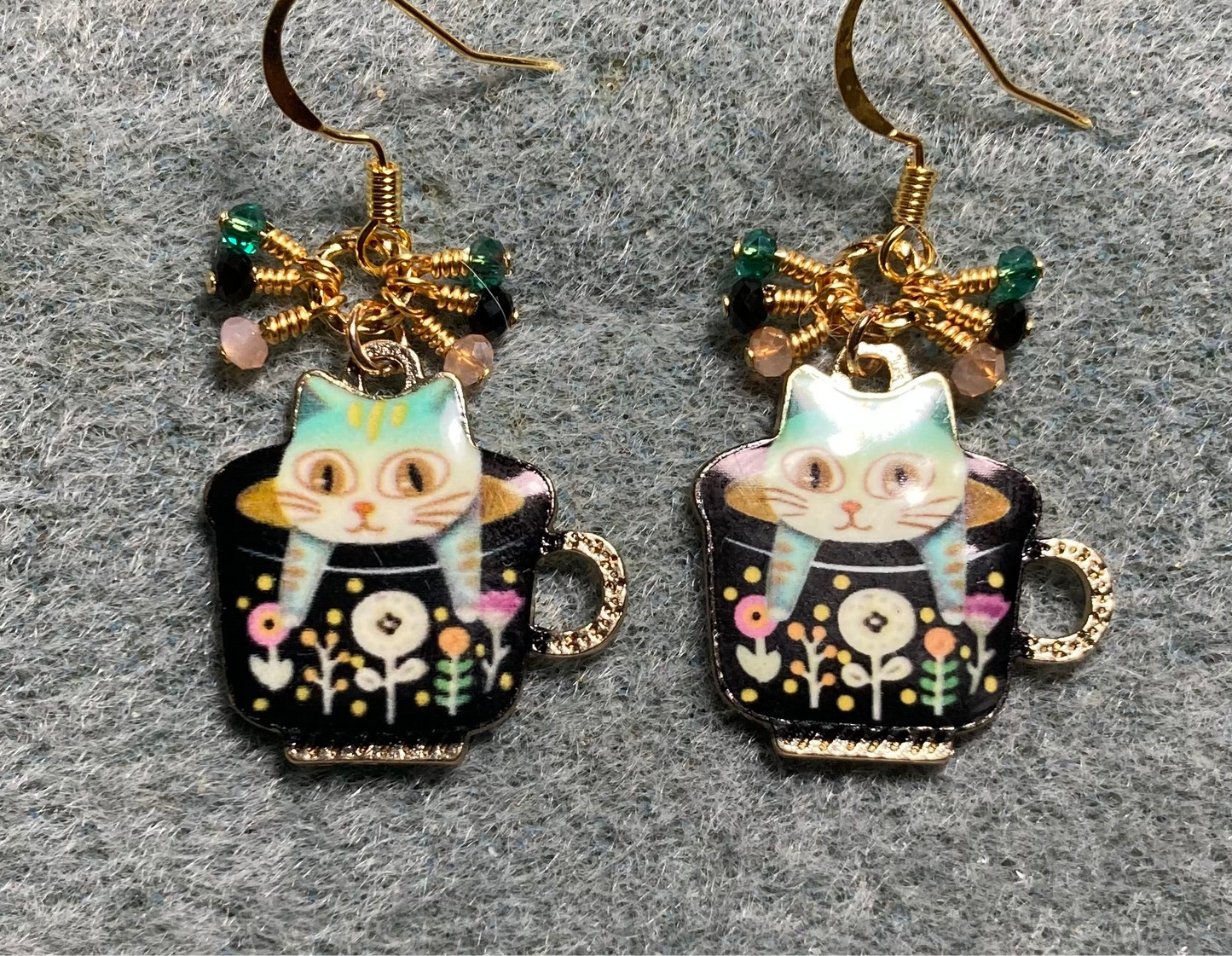 Black, teal, and peach enamel cat sitting in a cup charm earrings adorned with tiny dangling black, teal, and peach Chinese crystal beads.