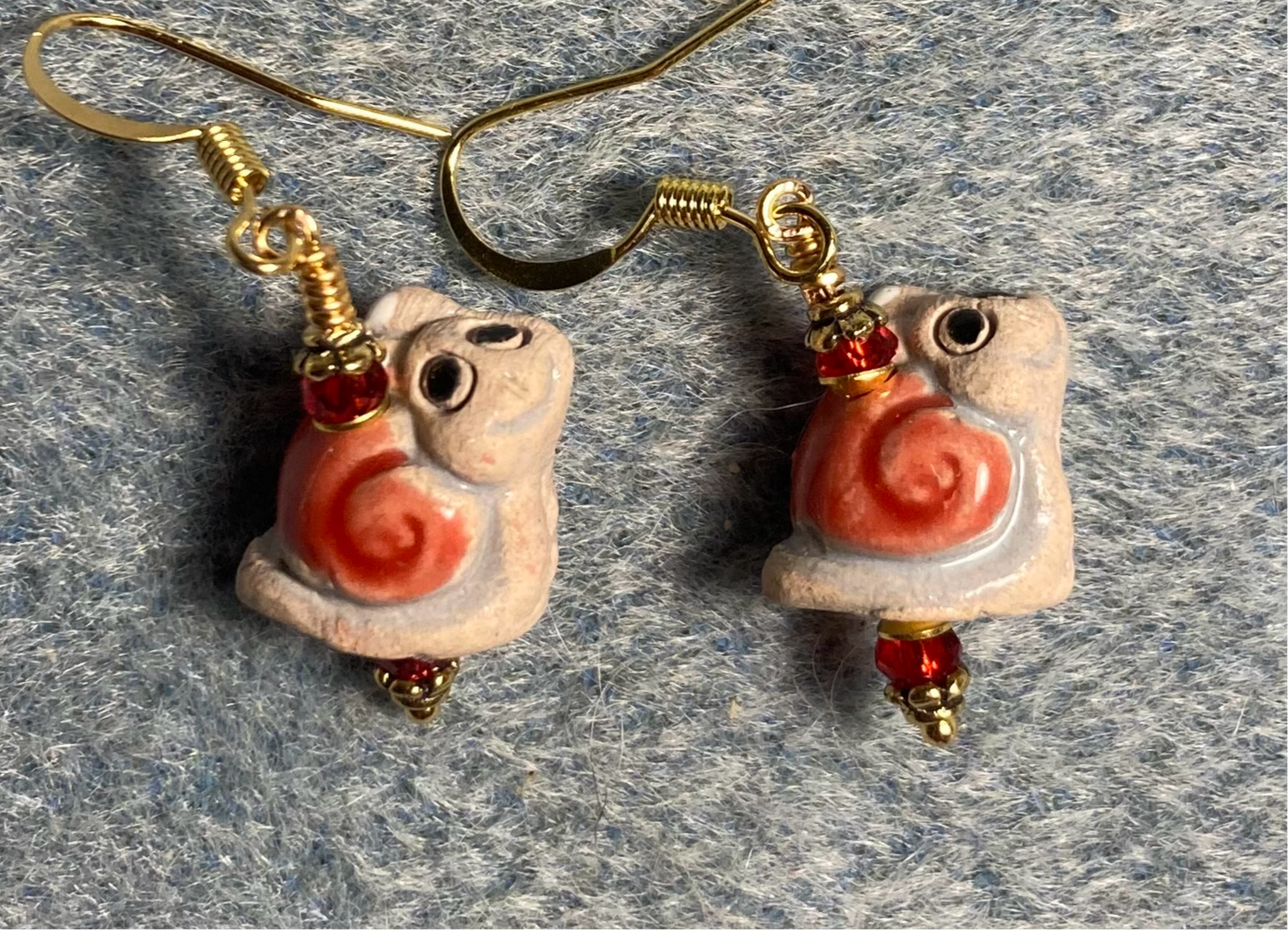 Small red and tan ceramic snail bead earrings adorned with red Chinese crystal beads.