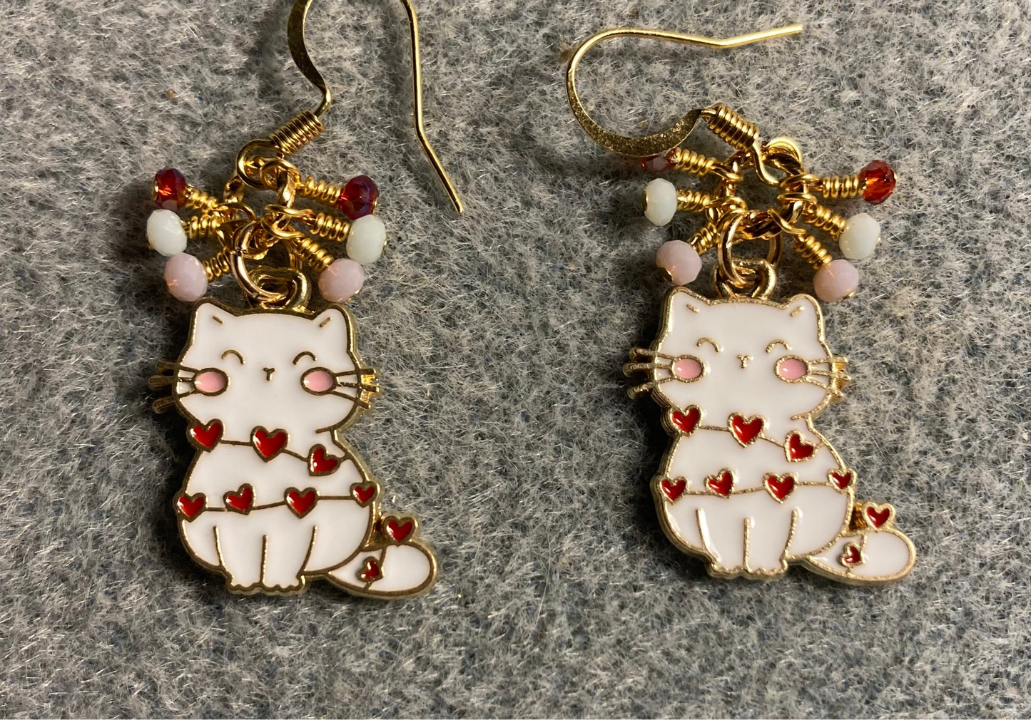 White, pink, and red enamel cat charm earrings adorned with tiny dangling white, pink, and red Chinese crystal beads.