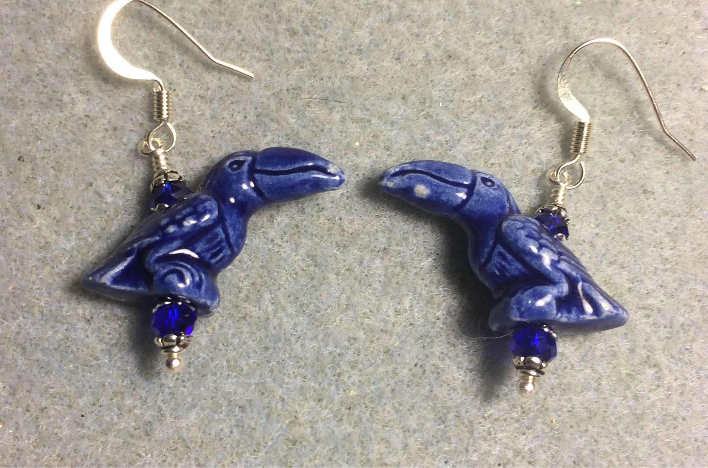 Dark blue ceramic toucan bead earrings adorned with dark blue Chinese crystal beads.