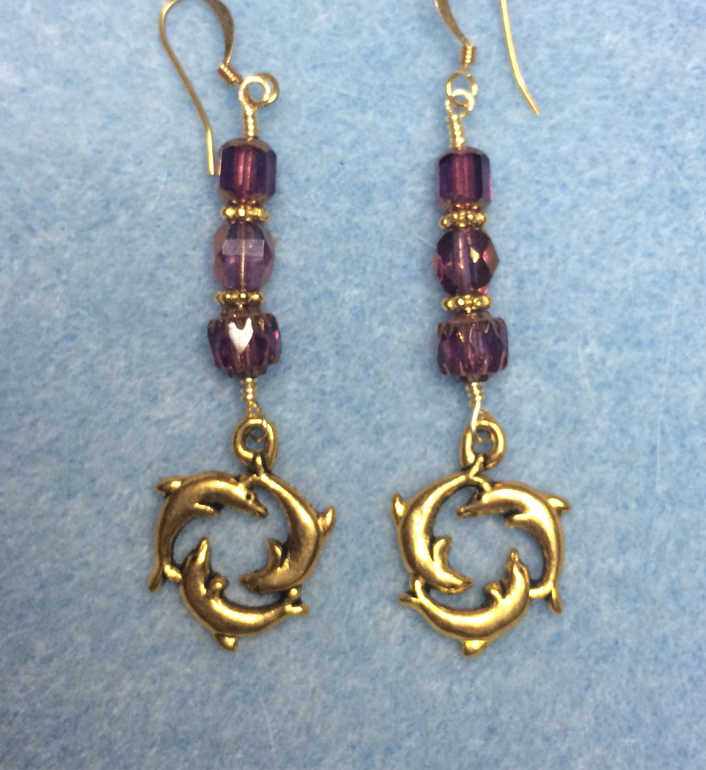 Gold circle of dolphin charm earrings adorned with purple Czech glass beads