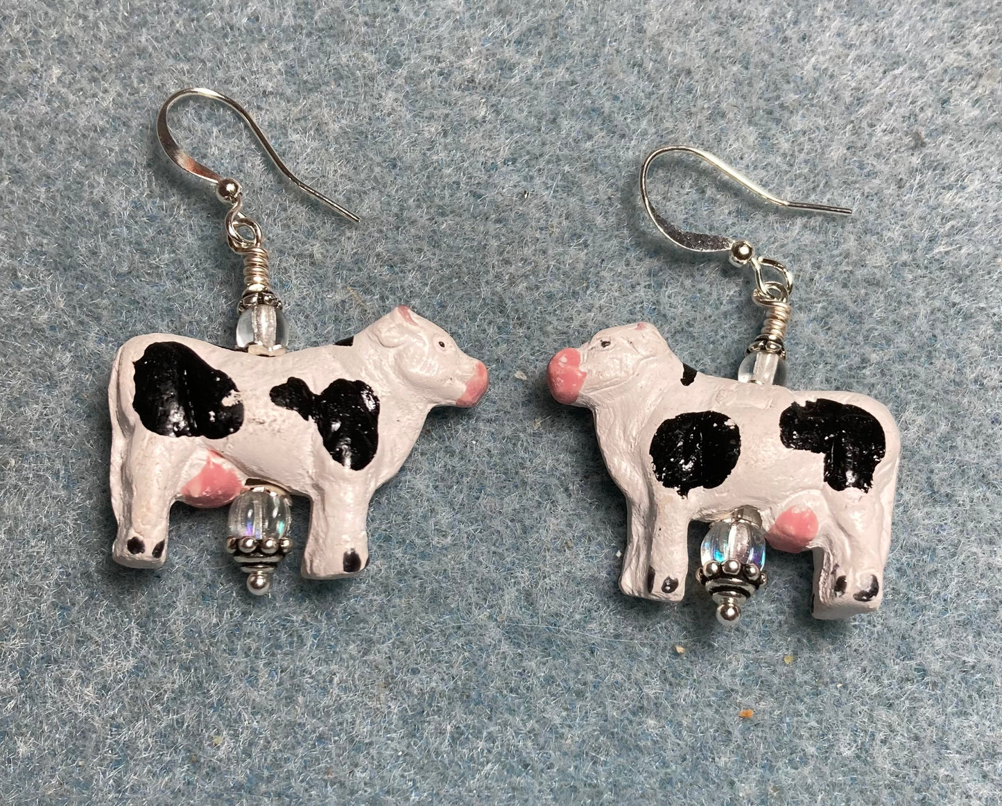 Large black and white ceramic cow bead earrings adorned with clear Czech glass beads.