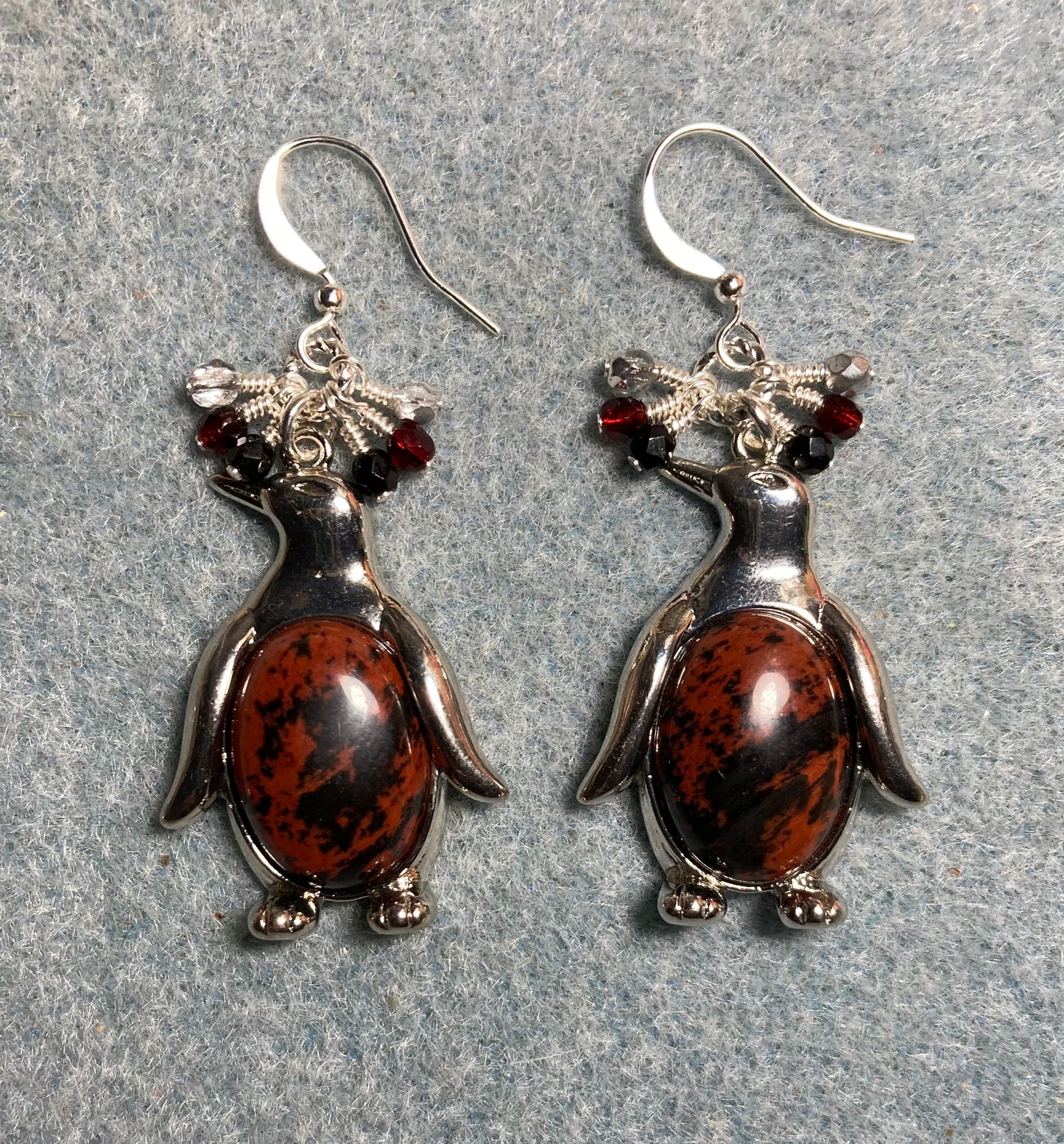 Large silver and red poppy jasper gemstone penguin charm earrings adorned with small dangling dark red, black, and silver Czech glass beads.