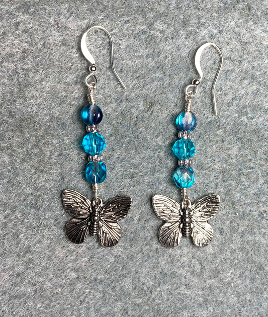 Silver butterfly charm earrings adorned with turquoise Czech glass beads.