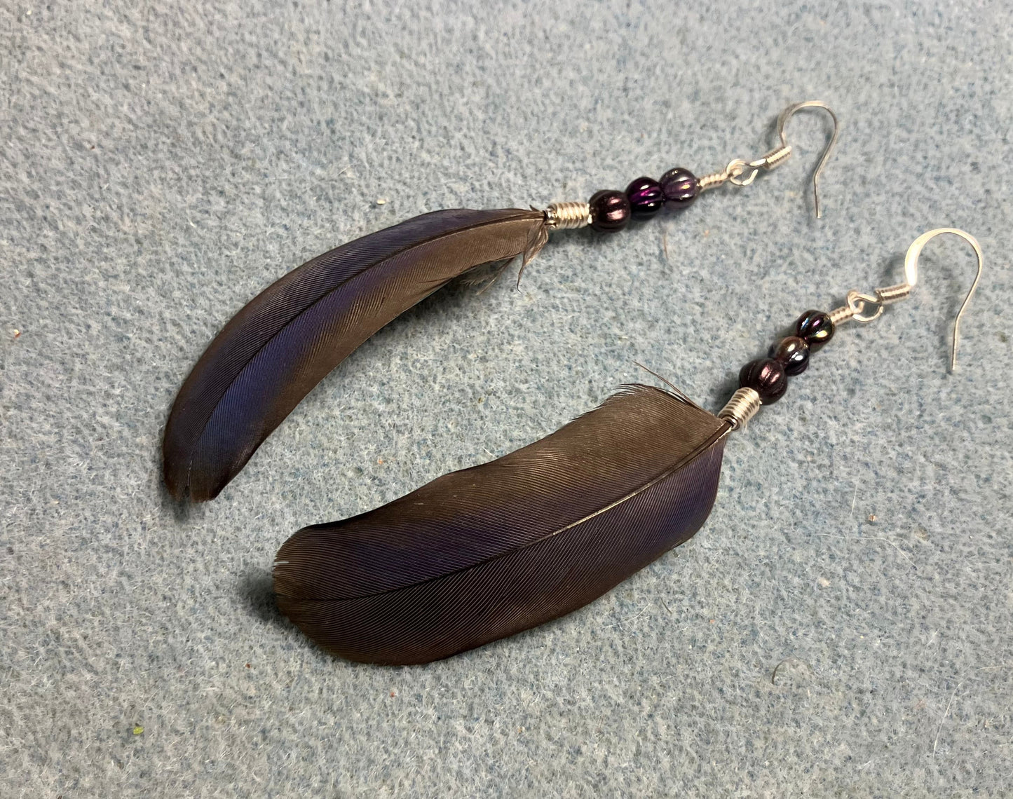 Purple Pionus parrot feather earrings adorned with small purple Czech glass melon beads.
