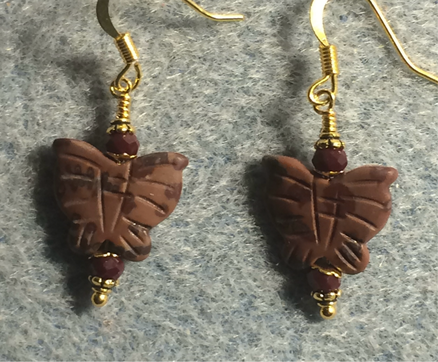 Red snakeskin jasper gemstone butterfly bead earrings adorned with dark red Chinese crystal beads.