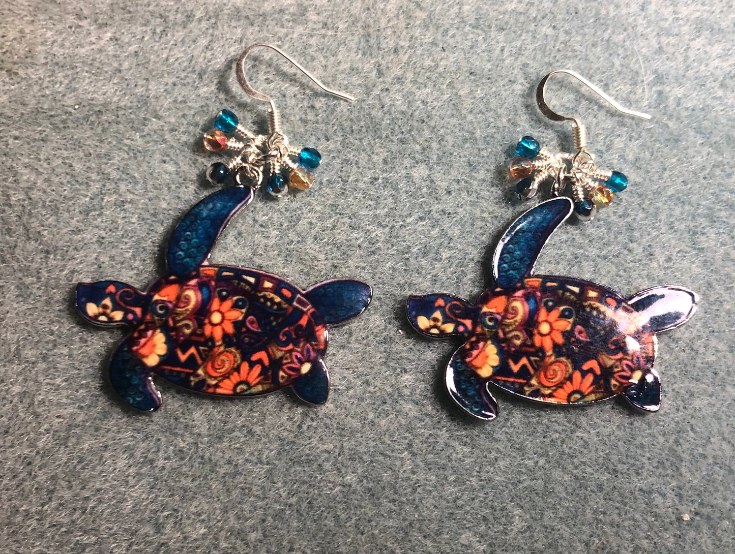 Large turquoise and orange enamel sea turtle charm earrings adorned with small dangling turquoise and orange Czech glass beads.