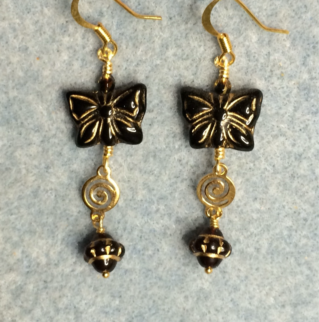 Black Czech glass butterfly bead earrings adorned with gold swirly connectors and black Czech glass Saturn beads.