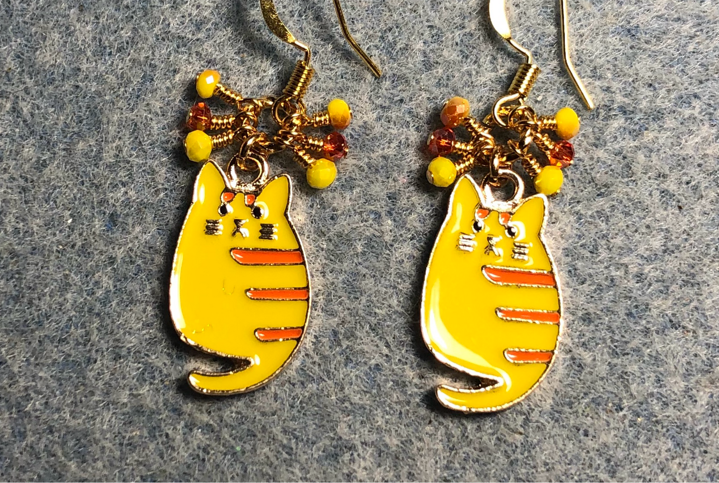 Yellow and orange enamel striped tabby cat charm earrings adorned with tiny dangling yellow and orange Chinese crystal beads.