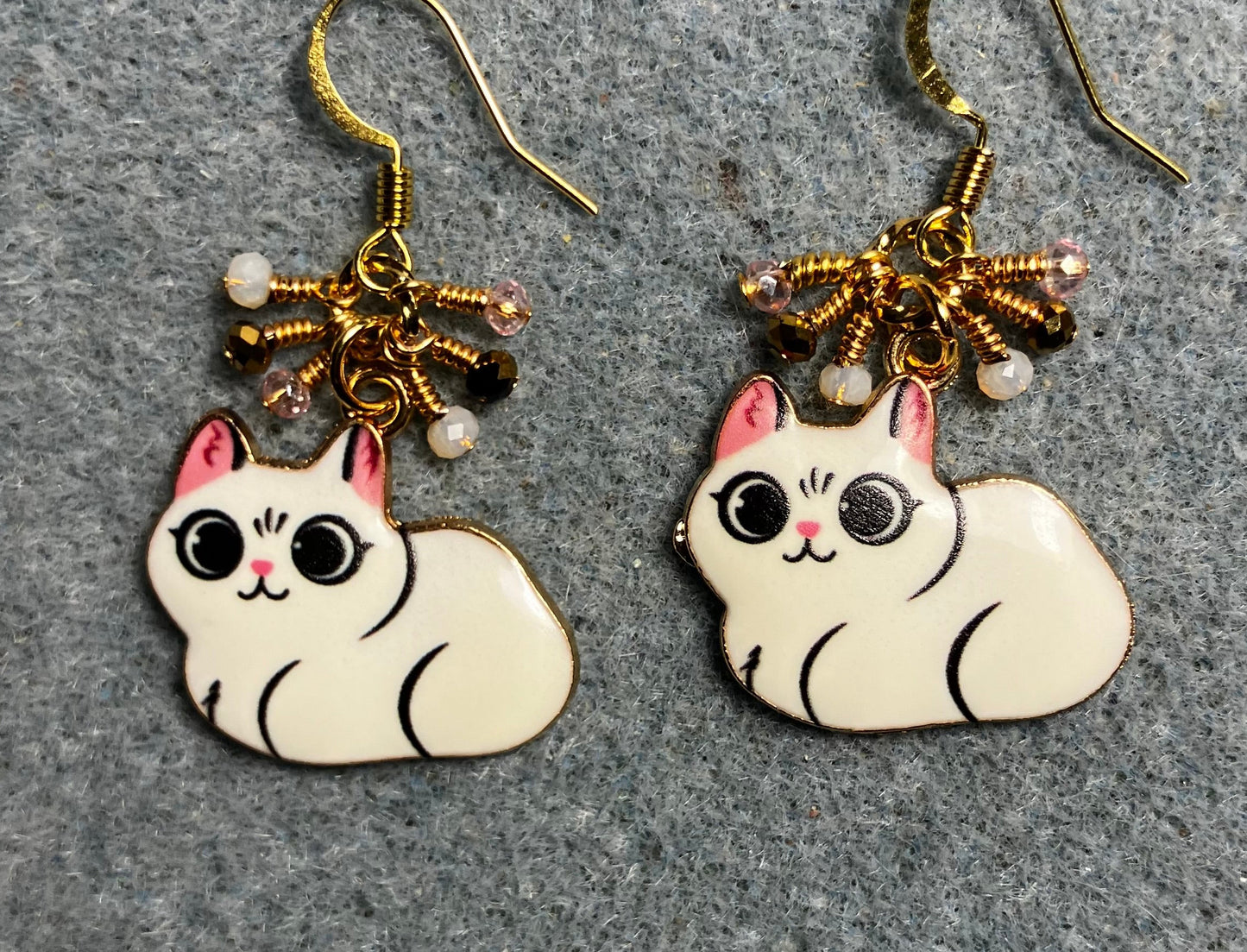 White, black, and pink enamel cat charm earrings adorned with tiny dangling white, black, and pink Chinese crystal beads.