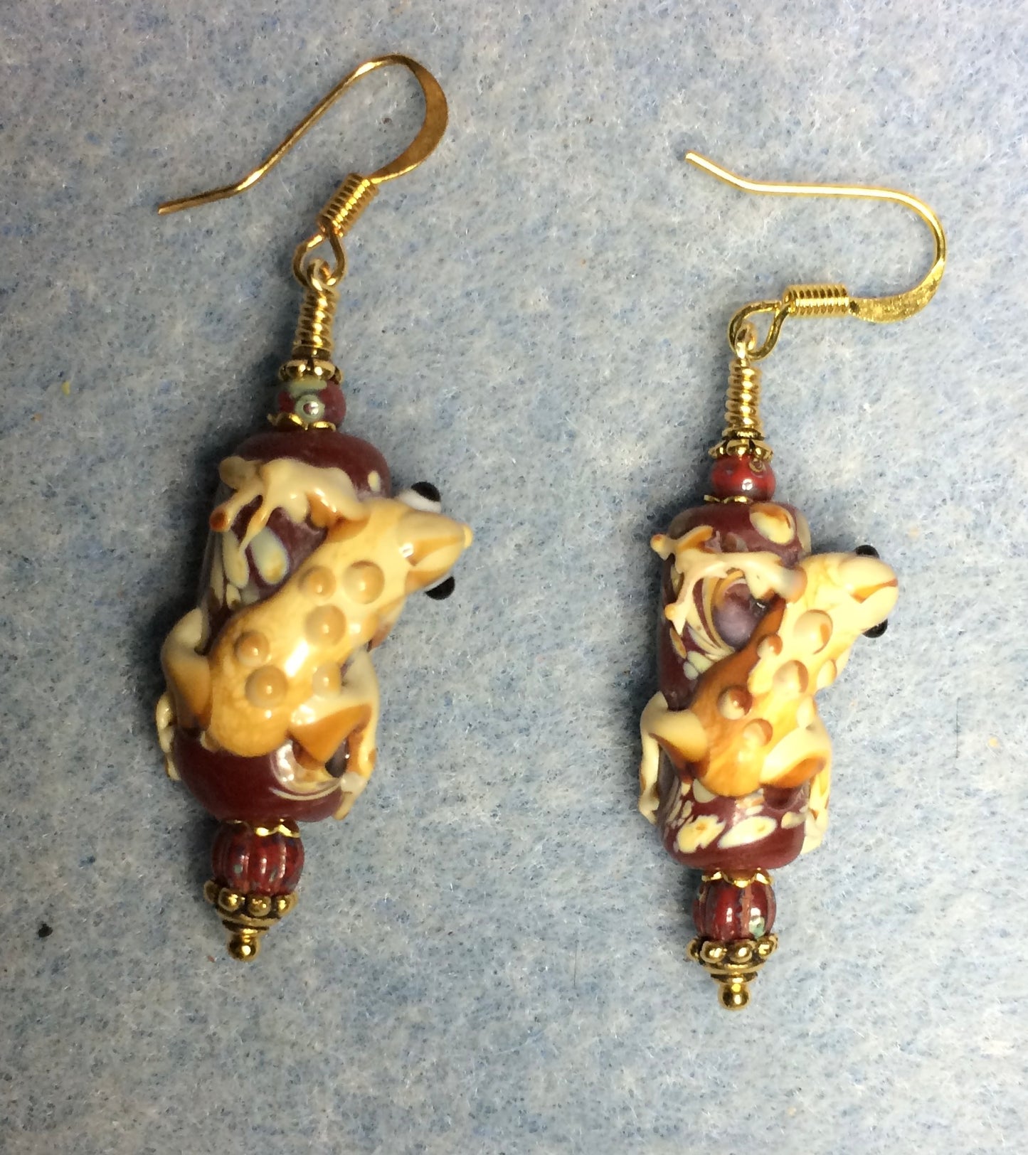 Red and tan lamp work lizard bead earrings adorned with dark red Picasso Czech glass beads.