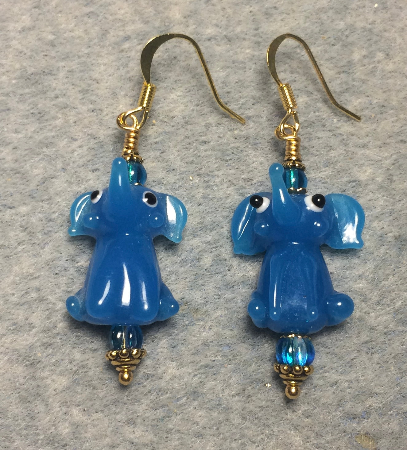Opaque turquoise lamp work sitting elephant bead earrings adorned with turquoise Czech glass beads.