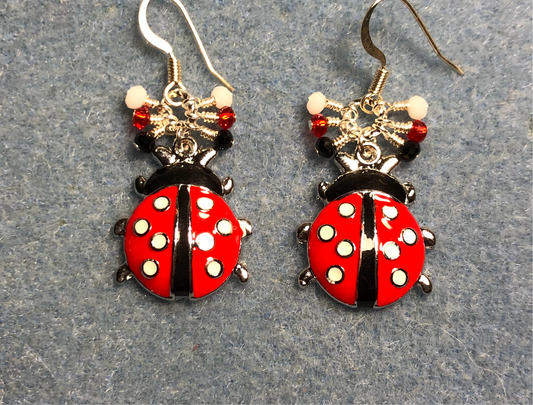 Red, black, and white enamel ladybug charm earrings adorned with tiny dangling red, black, and white Chinese crystal beads.